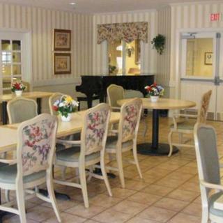 A cozy dining area with floral chairs and a piano in the background.