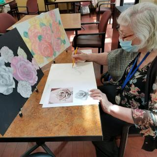 A woman engaged in painting flowers at an indoor art session.