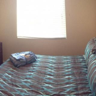 A neatly made bed in a bedroom with sunlight streaming through a window.