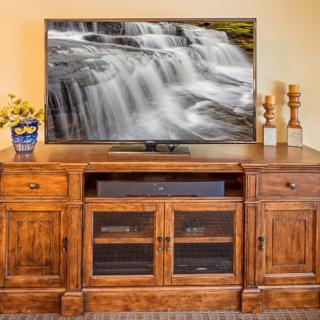A cozy living room setup featuring a television on a wooden entertainment center, displaying a serene waterfall image.