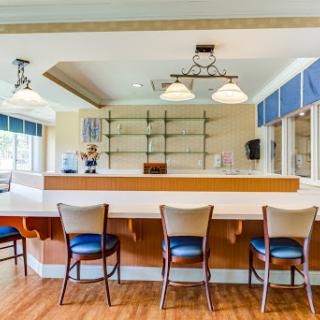 A modern bar setting with a clean design, featuring seating and ample natural light.