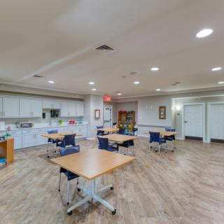 An empty classroom with tables and chairs arranged neatly.
