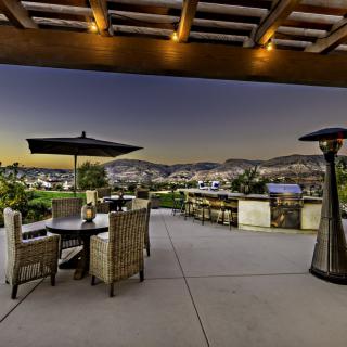 A scenic outdoor patio with a seating area overlooking hills at sunset.