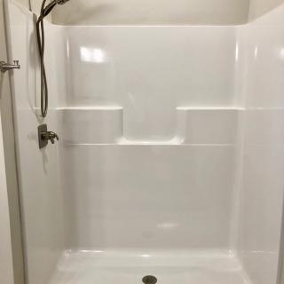 A clean white shower with built-in shelves and a showerhead.