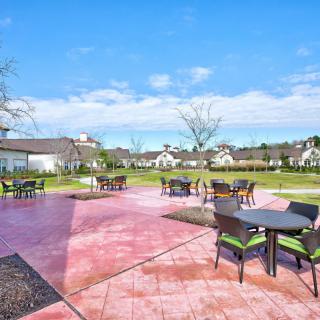 A sunny patio with tables and chairs under a clear blue sky.