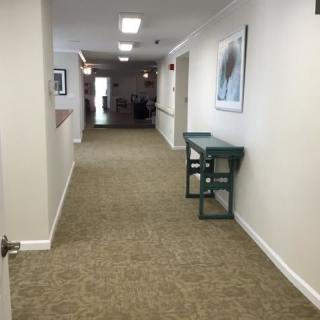 A well-lit hallway with carpet flooring and wall-mounted artwork.