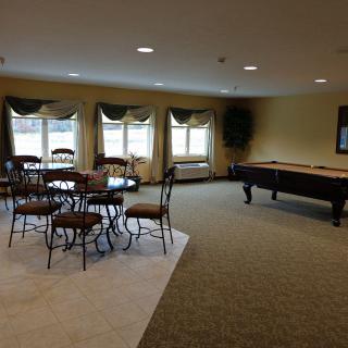 A spacious game room with a shuffleboard table and seating area.