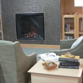 A cozy living room with a fireplace, two armchairs, and a small table with books.