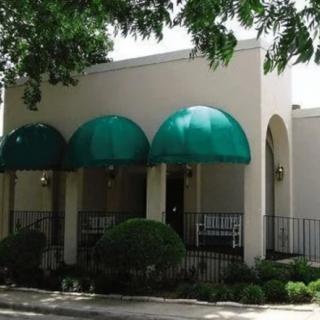 A building with green awnings and surrounding trees.