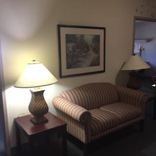 A cozy corner featuring a striped couch, matching lamps, and wall art.