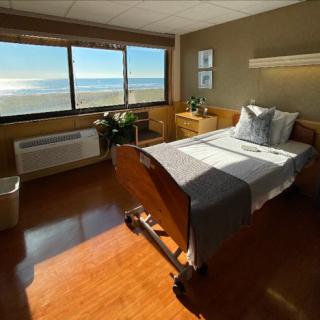 A serene hospital patient room featuring a bed with a view of the ocean.