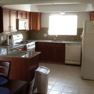 A modern kitchen with wooden cabinets and appliances, featuring a stove, refrigerator, and dishwasher.