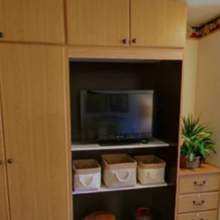 A cozy living room entertainment center with a television, storage baskets, and decorative elements.