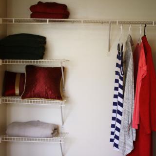 Organized closet with hanging clothes and neatly arranged shelves.