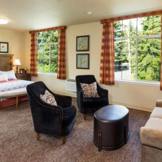 A cozy living area combined with a bedroom featuring comfortable seating and large windows.