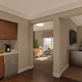 A modern living room with a kitchenette, leading to a cozy bedroom.