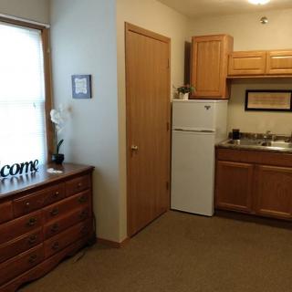 A cozy kitchen area with wooden cabinets, a refrigerator, and a window letting in natural light.