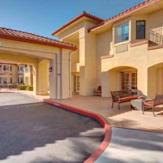 A Mediterranean-style residential building entrance with outdoor seating and a covered driveway.