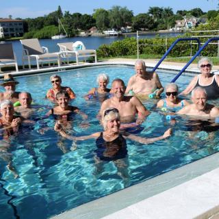 A group of people enjoying a swim in an outdoor pool on a sunny day.