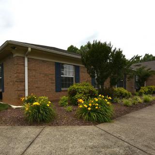 A brick house with well-maintained landscaping and colorful flowers.