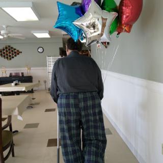 A person carrying colorful balloons in a festive event setting.