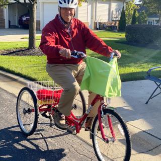 A person riding a tricycle with a helmet on in a residential area.