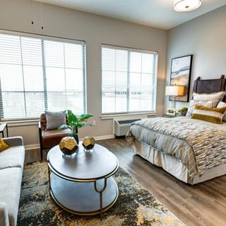 A modern and well-lit bedroom featuring a cozy bed, stylish furniture, and large windows allowing natural light to fill the space.
