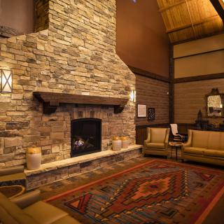 A cozy living room with a stone fireplace, warm lighting, and comfortable seating.