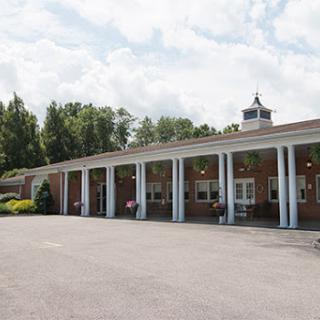 A view of a brick building with pillars, set against a cloudy sky.