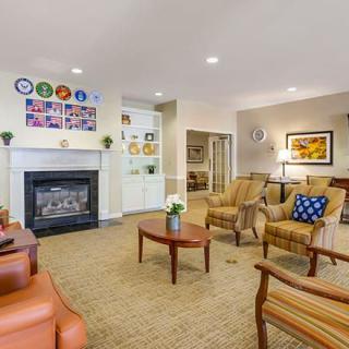 A cozy living room with a fireplace, comfortable seating, and decorative elements on the walls.