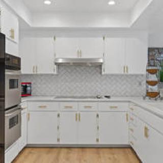 A modern kitchen with white cabinets, stainless steel appliances, and a tile backsplash.