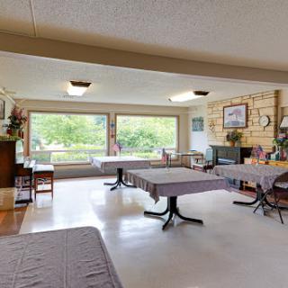 A spacious dining area with tables set for guests, bathed in natural light from large windows.