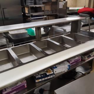 A stainless steel serving counter in a commercial kitchen, ready for food preparation and service.