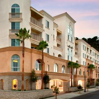 A modern residential apartment building with palm trees at sunset.