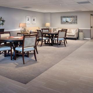 A modern dining area with neatly arranged tables and chairs, accented by soft lighting and a comfortable seating corner.