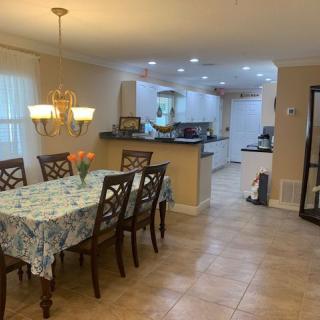 A cozy dining area with a table set for six, leading into an open kitchen space.