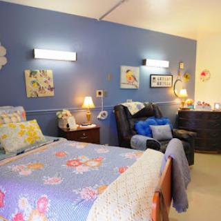 A cozy bedroom featuring blue walls, floral bedding, and stylish decor.