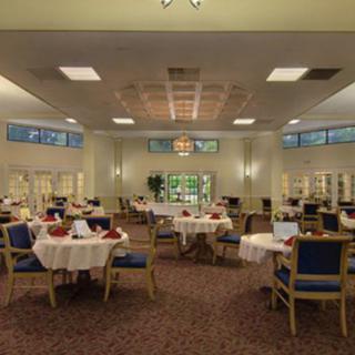 A spacious dining room with elegantly set tables and comfortable chairs, ready for guests.