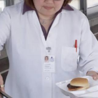 A person in a white uniform serving a sandwich.