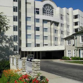A residential building with a landscaped entrance and colorful flowers in the foreground.