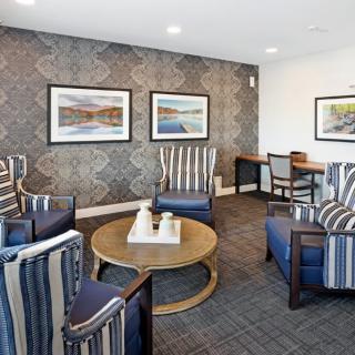 A stylish living room featuring striped armchairs, a round coffee table, and framed artwork on the wall.