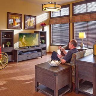 A man sits in a modern living room watching television, surrounded by stylish furniture and decor.