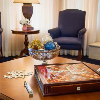 A cozy living room setting with armchairs, a coffee table featuring a Scrabble board, and decorative items.