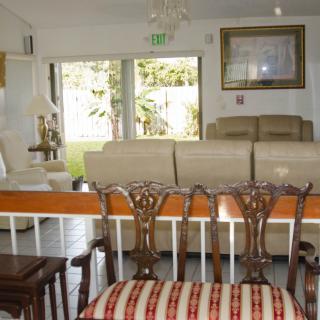 A cozy living room with a variety of seating options including chairs and a couch near large windows.