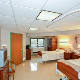 A serene and well-organized patient room in a hospital, featuring two beds and ample natural light.