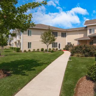A well-maintained residential apartment complex with a paved walkway and lush landscaping.