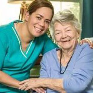 A caregiver and an elderly woman smiling together, showcasing supportive home care.