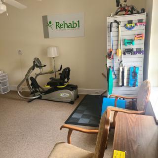 A rehabilitation room featuring an exercise bike, therapy equipment, and a comfortable seating area.