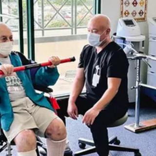 A therapist guides a patient through an exercise in a rehabilitation setting.