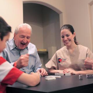 A joyful family game night featuring a child, an elderly man, and a caregiver enjoying their time together.